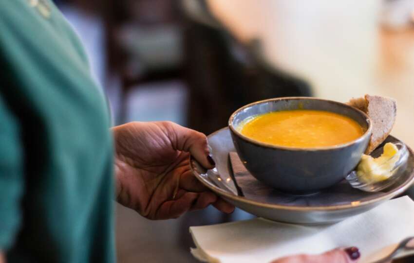 person carrying bowl of soup